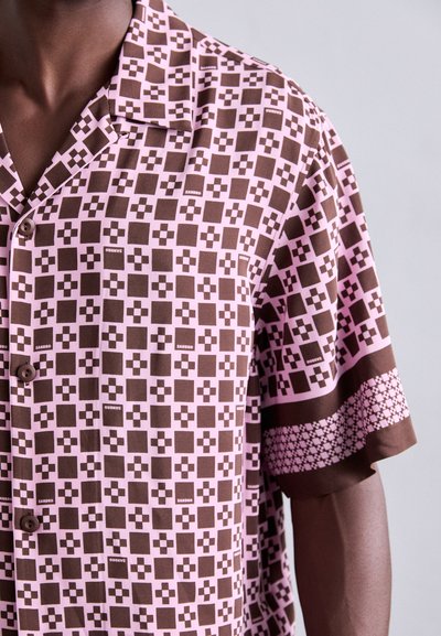 Chemise à manches courtes en brun et rose avec un motif géométrique, fermeture à boutons et bordure à motifs contrastants le long des manches.