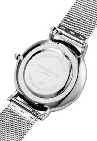 Cassa rotonda in acciaio inossidabile con fondo lucido, caratterizzata da dettagli incisi e un bracciale in maglia argentata. Hardware e chiusura visibili.