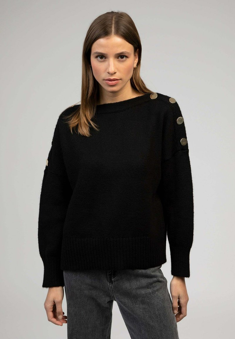 Pull en maille noir à coupe ample, avec un large col, un ourlet côtelé et des accents de boutons en métal doré sur les épaules.