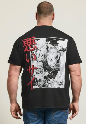 Mann trägt schwarzes T-Shirt mit großer schwarz-weißer Illustration eines Nashorns, das durch Trümmer bricht, und roten japanischen Zeichen.