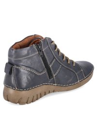 Bottine bleu foncé avec lacets beige, fermeture éclair latérale, coutures visibles et semelle brune texturée vue de profil extérieur.
