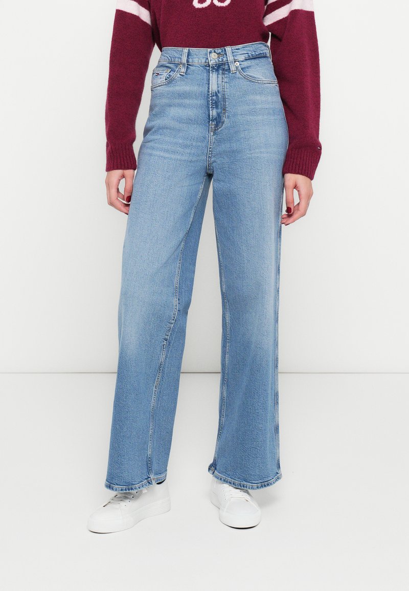 Világoskék, magas derekú farmernadrág széles szárú szabással, fakult hatással, varrott részletekkel és klasszikus ötpántos zsebdizájnnal.