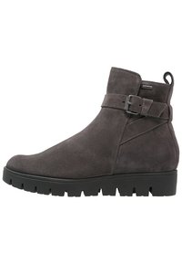 Bottines en daim gris avec une semelle en caoutchouc noir épaisse et une sangle ajustable avec une boucle en métal autour de la cheville.