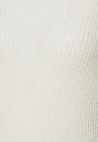 Weißer Strickpullover mit strukturierter Oberfläche und geripptem Muster, mit einem runden Halsauschnitt. Der Stoff zeigt eine weiche, leichte Konstruktion.