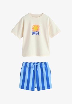 Kurzärmeliges cremefarbenes T-Shirt mit einer gelben Sonne und dem Schriftzug "SOLEIL", kombiniert mit blauen, gestreiften Shorts mit elastischem Bund.