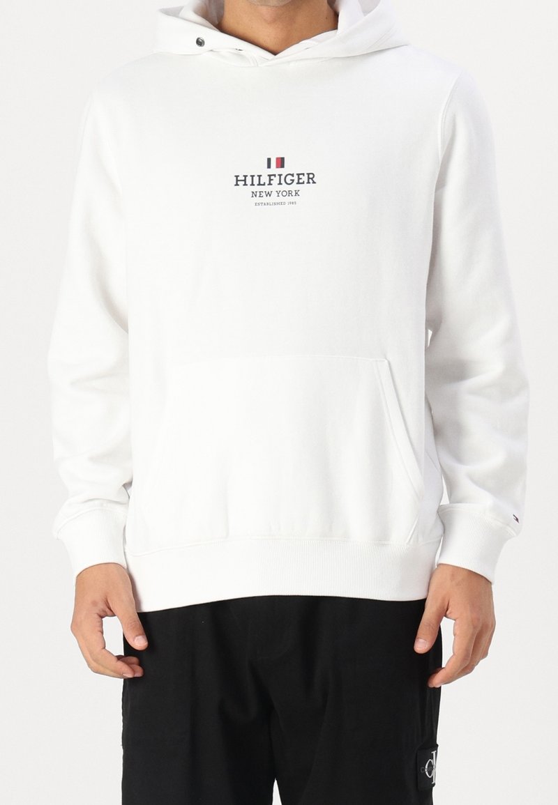 Bílá mikina s kapucí a přední kapsou, s logem "HILFIGER NEW YORK" v námořnické barvě. Hladké manžety a lem, měkká textilní struktura.