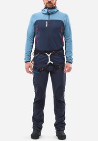 Blue fleece jacket with red accents and full zipper, paired with navy outdoor pants featuring multiple pockets and adjustable straps.