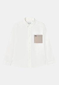 Camicia bianca a maniche lunghe con colletto, dotata di taschino beige sul petto e logo verde. Realizzata in un tessuto liscio.