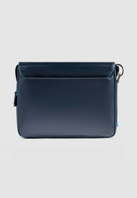 Marineblaue Umhängetasche aus Kunstleder mit glatter Textur, Klappenverschluss, Vordertasche und kontrastierendem türkisfarbenem Reißverschlussdetail.