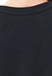 Navyfarbener, gestrickter Pullover mit geripptem Halsausschnitt, weicher Textur und nahtlosem Rücken. Minimalistisches Design ohne sichtbare Muster oder Akzente.