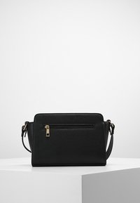 Borsa a tracolla nera in pelle texturizzata con tasca anteriore con zip, hardware in tono oro e tracolla regolabile. Forma rettangolare.