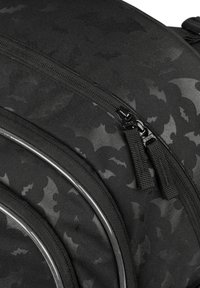 Czarny plecak z wzorem nietoperzy, wykonany z fakturowanej tkaniny, z podwójnymi suwakami. Wykończony błyszczącym oberżynowym kantem.