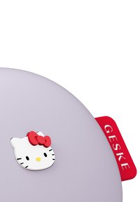 Contenitore rotondo viola con un volto di Hello Kitty bianco e fiocco rosso. Dotato di manico rosso con la scritta "GESKE" incisa. Texture liscia.