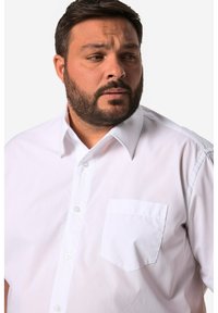 Camicia bianca con bottoni, dotata di una tasca sul petto, caratterizzata da un colletto classico e maniche corte in un morbido tessuto misto cotone.