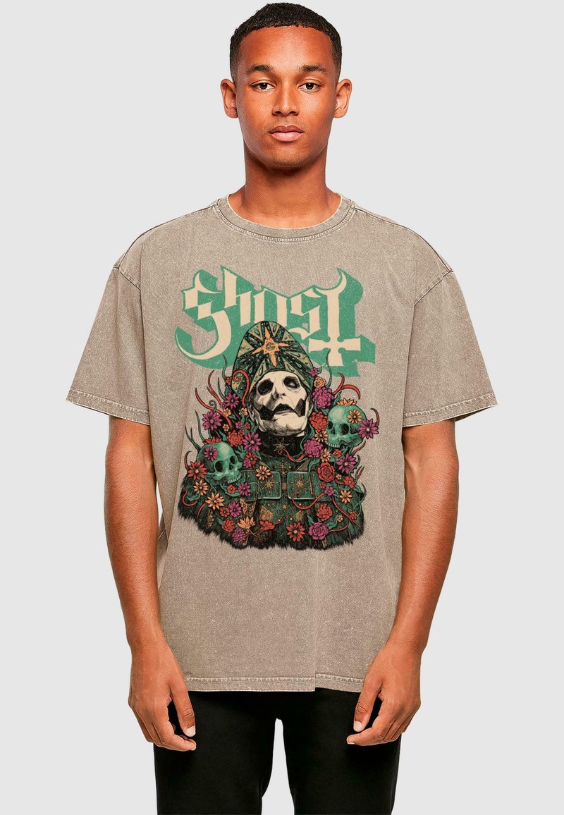 Graphic oversized t-shirt in tan, featuring a central illustration of a skull surrounded by flowers, accented with the word "Ghost" in green.