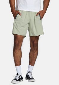 Shorts vert clair en tissu doux, dotés de poches latérales avec des accents gris et d'une ceinture élastique confortable.