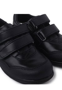 Scarpe nere con una combinazione di materiali lisci e testurizzati, due cinturini in velcro e una punta arrotondata.