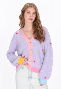 Cardigan lavandă cu modele de inimi multicolore, bordură roz și închidere cu nasture. Prezintă manșete ribbate în galben și albastru.