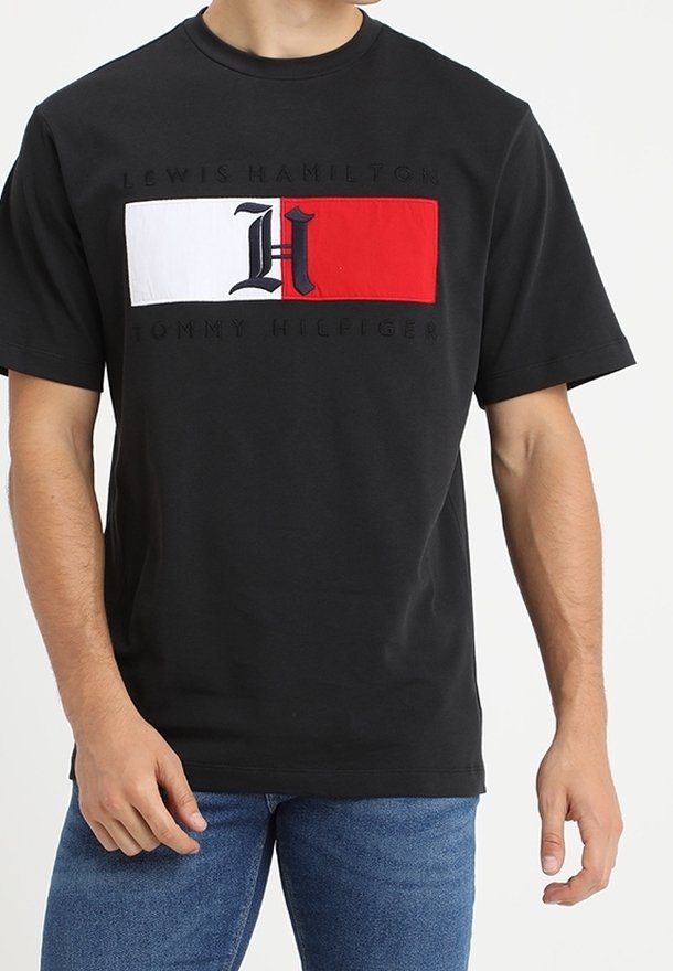Czarny bawełniany t-shirt z wyraźnym logo w kolorach czerwonym, białym i niebieskim na przodzie, z krótkimi rękawami i okrągłym dekoltem.