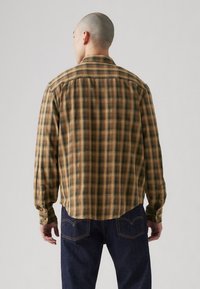 Braun und grün kariertes Hemd mit Kragen, langen Ärmeln und abgerundetem Saum. Der Stoff wirkt strukturiert und hat ein weiches, flanellartiges Finish.