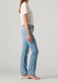 Vaaleansiniset farkut, joissa on korkeahko vyötärö, suorat lahkeet ja hienovaraiset ompeluvarjostukset. Yhdistetty yksinkertaiseen valkoiseen lyhythihaiseen toppiin ja sandaaleihin.