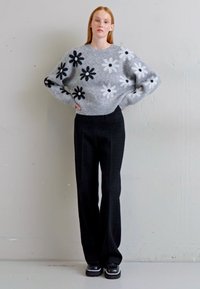 Grå sweater med sorte og hvide blomster mønstre, parret med sorte vide bukser og sorte platform sko. Sort mélange, afslappet pasform.