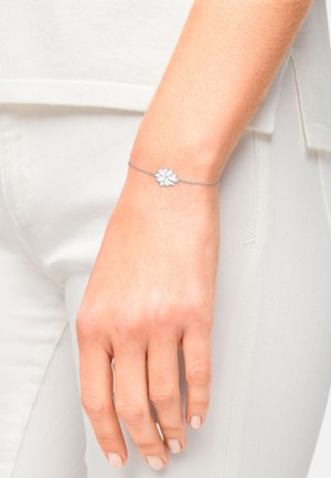 Bracciale in argento con motivo floreale, montato su una catena fine con una texture delicata. Il design include accenti a strati simili a petali.