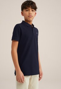 Tamsiai mėlynas medvilninis polo marškinėliai su trumpomis rankovėmis, trijų mygtukų apykaklė ir siuvinėtas logotipas ant kairės krūtinės. Lygi tekstūra.