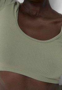 Gerippter Crop-Top in gedämpftem Grün, mit weitem Rundhalsausschnitt und figurbetonter Silhouette, aus dehnbarem Stoff für zusätzlichen Komfort.