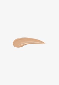 Échantillon de fond de teint beige crémeux avec une texture lisse, une forme fluide et un éclat subtil sur un fond blanc.