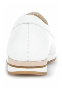 Chaussure en cuir blanc à enfiler, de forme arrondie, avec une couture à l'arrière et un détail de semelle beige et marron.