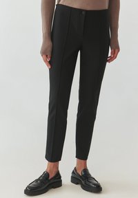 Pantaloni negri la comandă dintr-un material neted, cu un design potrivit, pliuri și închidere cu button. Asortați cu mocasini negri.