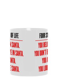 Taza de cerámica blanca con texto rojo que presenta las frases "CREO EN SANTA" y "CUATRO ETAPAS DE LA VIDA" en una fuente sans-serif negrita.