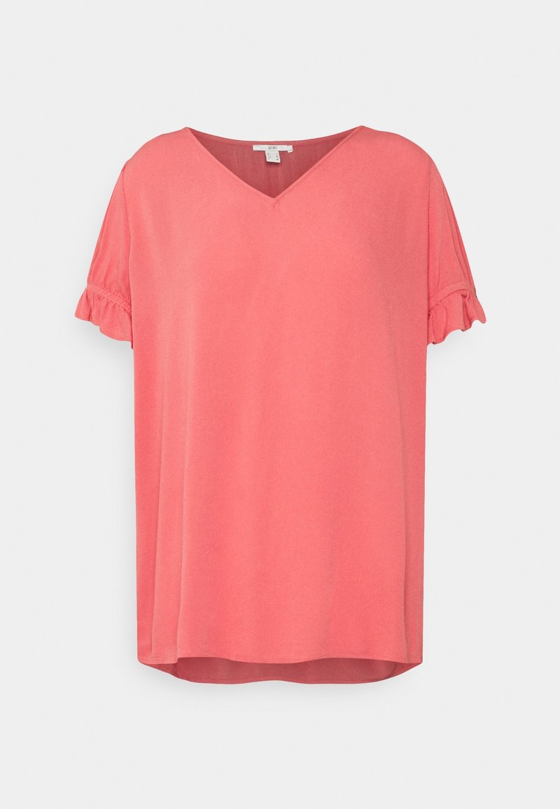 Top en color coral rosa con escote en V, mangas cortas con volantes y un corte relajado. Fabricado en una tela suave con una textura lisa. Dobladillo redondeado en la parte inferior.