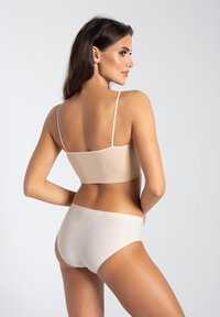 Beżowy, prążkowany, bezszwowy biustonosz oraz pasujące majtki bikini z cienkimi ramiączkami. Gładka faktura, dopasowany krój oraz minimalistyczny styl.