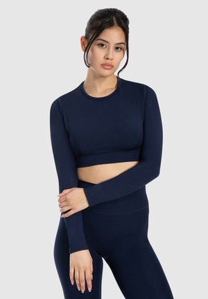 Marineblaue langärmelige Crop-Top aus dehnbarem Material mit Rundhalsausschnitt und tailliertem Design, kombiniert mit passenden hoch geschnittenen Leggings.