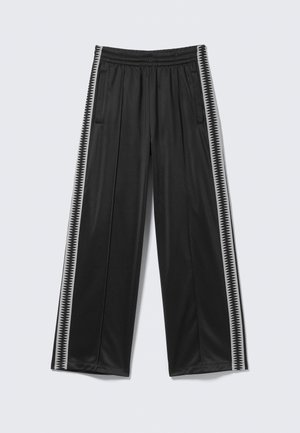 Pantalones de pierna ancha negros, hechos de una tela suave. Cuentan con una cinturilla elástica y bolsillos laterales. Dos franjas blancas verticales con un patrón en zigzag.