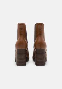 Brown leather ankle boots with a textured brown block heel, elastic side panels, and pull tabs at the back for easy wear.