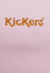 Tecido canelado de cor rosa clara com o logótipo "Kickers" bordado em amarelo dourado. O material parece macio e com um acabamento texturizado.