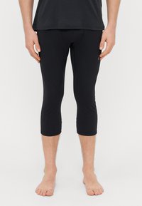 Black capri leggings made of smooth, stretchy material, featuring a snug fit that ends below the knee and a small logo detail on the side.