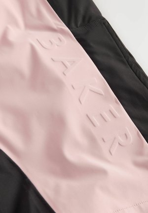 Juodos ir rožinės sportinės aprangos medžiaga su tekstūruotu, iškilios "BAKER" logotipu rožiniame panele ir lygiomis juodomis detalėmis.