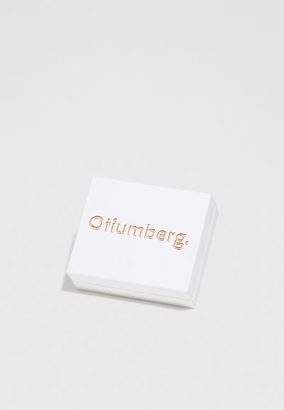 Valge ristkülikukujuline kast, millel on sile tekstuur, peal on reljeefne kuldne kiri "Ofiumberg." minimalistlikus disainis.