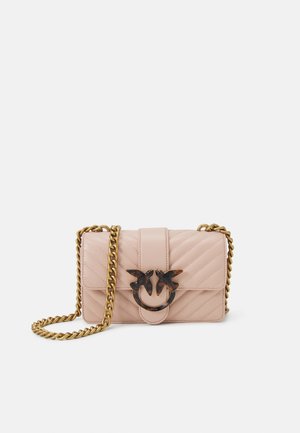 Jasnoróżowa pikowana torebka na ramię z złotym łańcuszkowym paskiem i ozdobnym złotym oraz żółwiopodobnym zapięciem w kształcie ptaka na przedniej klapie.