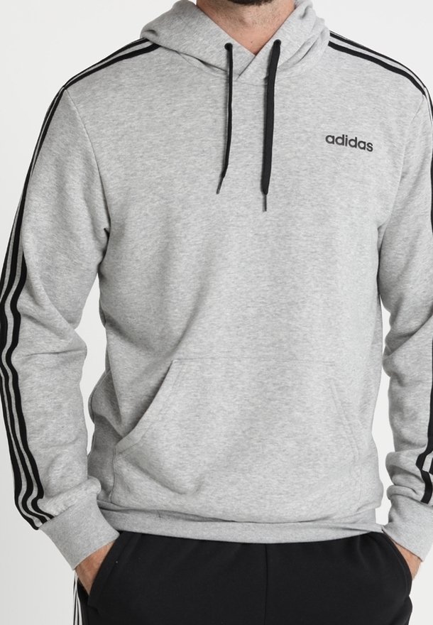Felpa grigia in tessuto morbido con tasca a marsupio, cordini neri e tre strisce nere che scorrono lungo le maniche. Logo "adidas" sul petto.