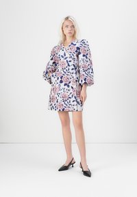 Λουλουδιαστό φόρεμα με V-ντεκολτέ, φουσκωτά μανίκια και τσέπες. Διαθέτει ανοιχτό μπλε φόντο με ροζ και ναυτικό μοτίβα λουλουδιών. Μαύρες γόβες συμπληρώνουν την εμφάνιση.