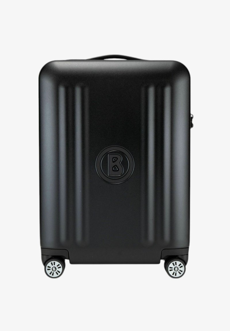 Zwarte harde koffer met verticale ribbels, een rond logo en vier multidirectionele wielen voor gemakkelijke mobiliteit.