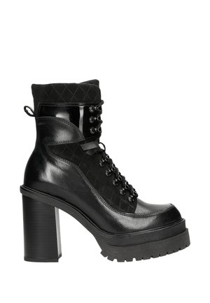 Black ankle boot with a glossy leather finish, lace-up front, quilted textile top, and chunky heel with textured sole.