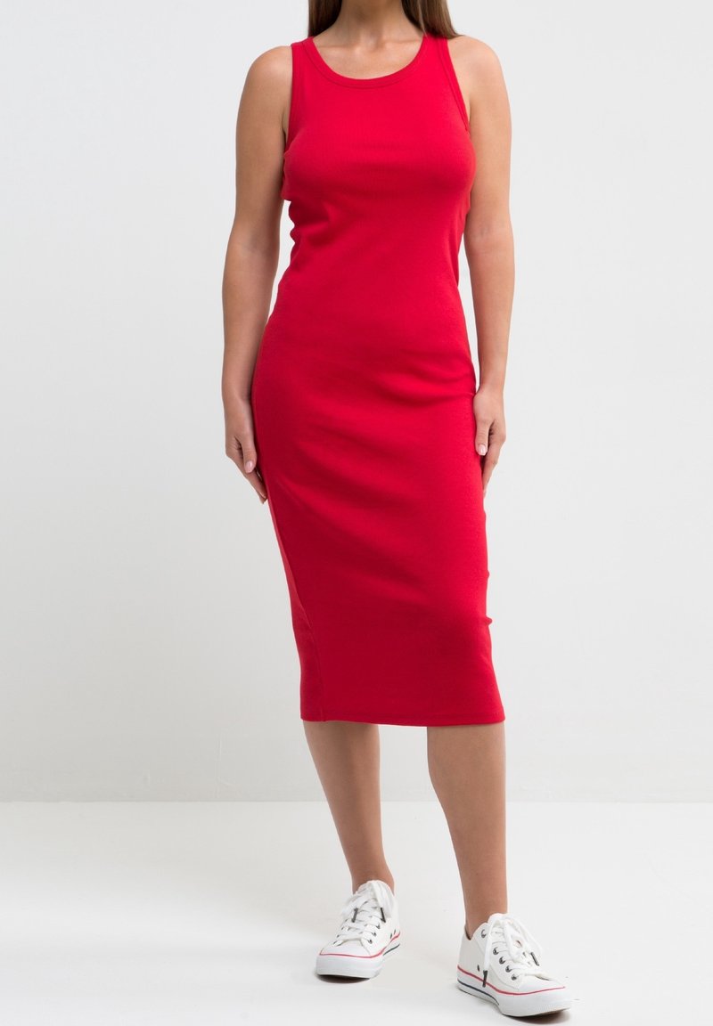 Robe midi rouge à rayures avec un col rond et sans manches, associée à des baskets blanches basses. Texture lisse et silhouette ajustée.