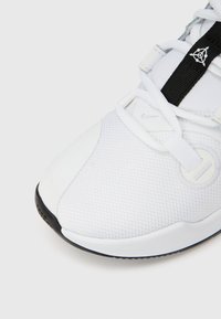 Λευκό αθλητικό παπούτσι με επάνω μέρος από πλεκτό ύφασμα, ελαστική σόλα και μαύρη διακοσμητική ρίγα. Διαθέτει στρογγυλεμένη μύτη και ελάχιστη σήμανση.