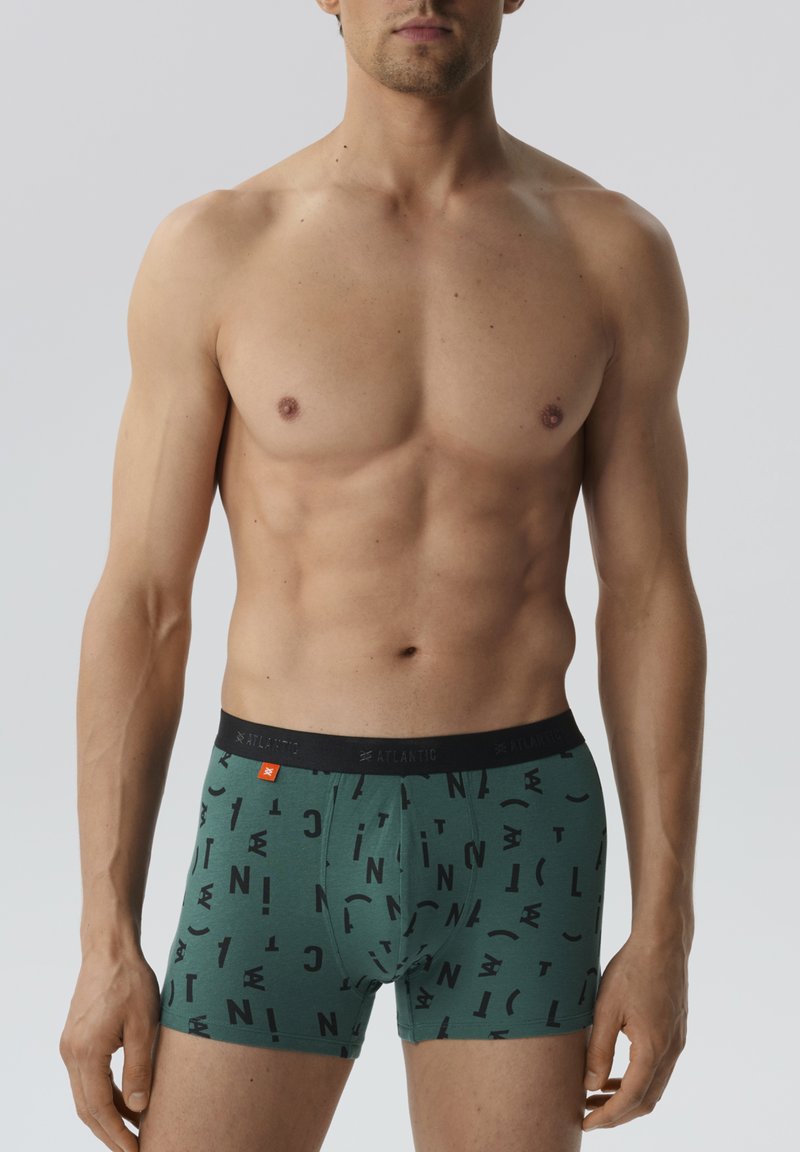 Męskie bokserskie slipy w kolorze zielonym z graficznym wzorem w wyraźne czarne litery. Elastyczny pas z logo marki, materiał z domieszką bawełny.